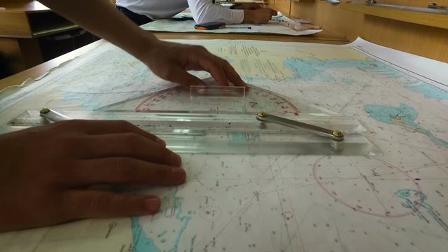 Two men in hand-calculate the route on the map with a compass