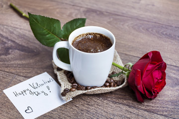 coffee cup with red rose and valentines day message card on a book