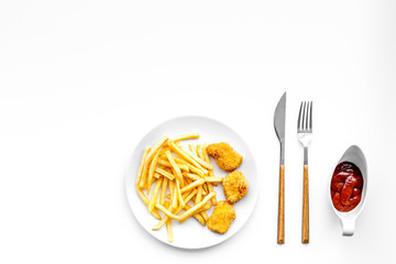 Fast food reastaurant. Chiken nuggets and french fries on plate on white background top view space for text