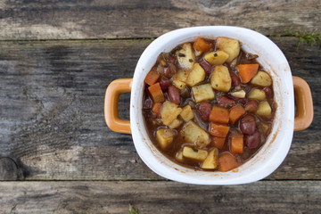 Appetizing beautiful soup with potatoes, onions, carrots and beans. On an old wooden background and close-up. Top view and copy space.