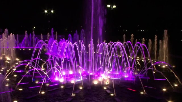Dancing fountains of ultraviolet colors in Moscow at night. Beautiful views of capital of Russia. Bright colorful water on black sky background in big city.
