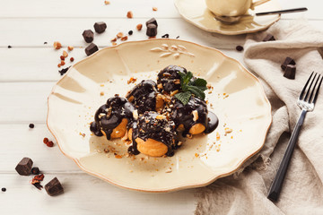 French profitroles with chocolate icing and mint leaves