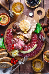 Mix of different snacks and appetizers: sausage, bread, olives, cheese, chestnuts, peas and beer on wooden board. Top view.
