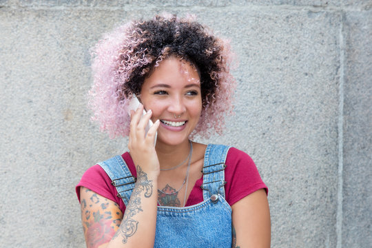 Punkgirl mit rosa Haaren am Telefon