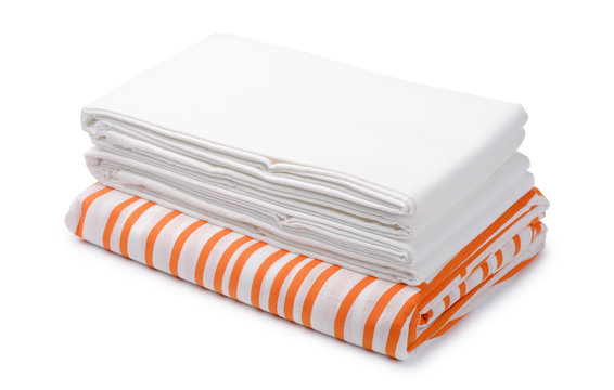 Stack of folded white and color bedding sheets