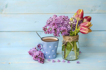 cup of coffee with milk and bouquet of lilac on   wooden background