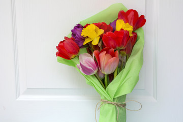bouquet of colorful tulips wrapped in green paper on  a wooden  background 