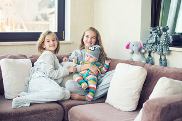 Beautiful toddler girl kissing her little brother at home, laughing and embracing with love and care