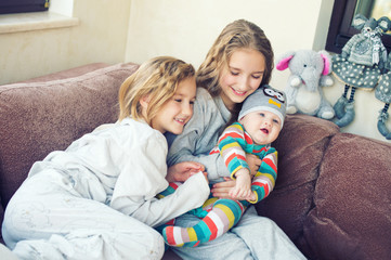 Beautiful toddler girl kissing her little brother at home, laughing and embracing with love and care