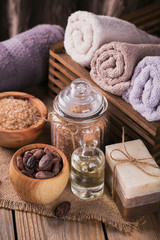 Natural cosmetic oil, sea salt and natural handmade soap with cocoa beans on rustic wooden background