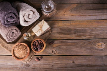 Natural cosmetic oil, sea salt and natural handmade soap with cocoa beans on rustic wooden background