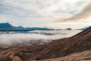 Slope of Bromo volcano (Gunung Bromo) to base groove rock and ground sand with cloud and mountain background,. Bromo Tengger Semeru National Park, East Java, Indonesia