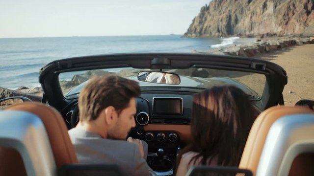 Cheerful couple on the vacation journey by a convertible