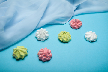 Multi Colored sweet meringue traditional form isolated on blue background.