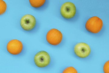 Top view of colorful fruit pattern of fresh orange and apple on blue background