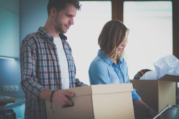 Couple unpacking cardboard boxes in their new home. Young couple.