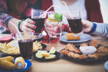 Top view of group of people having dinner together while sitting at wooden table. Food on the table. People eat fast food.