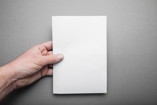 Blank sheet A5 for design, a mock-up in the hand of a European man.
