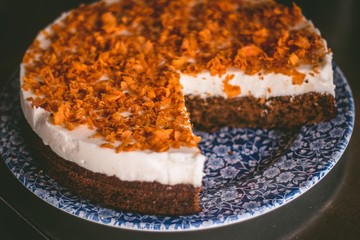 Close up of a traditional carrot cake on a blue plate with floral ornaments