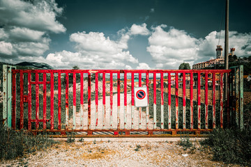 Red gate blocking access to a dirt road in the Tuscan countryside, block concept