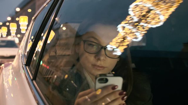 Woman Looking Through the Car Window and at her Mobile