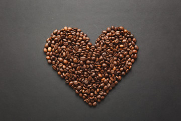 Brown coffee beans in form of heart isolated on black texture background for design. Saint Valentine's Day card on fabruary 14, holiday concept.