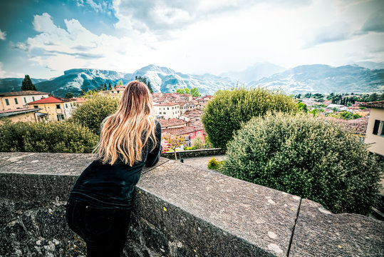 Young woman overlooking the terrace of Barga, Lucca, Tuscany, admires the mountains on the horizon
