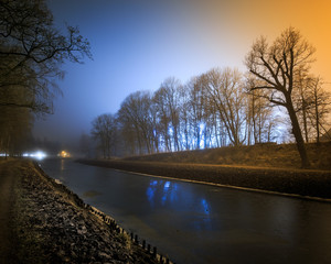 Blue and yellow misty night at canal