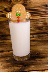 Gingerbread man in a glass of milk on wooden table