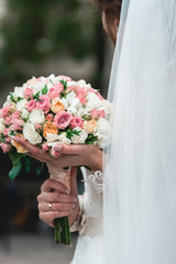 bride in a luxurious wedding dress holding a wedding bouquet made of roses