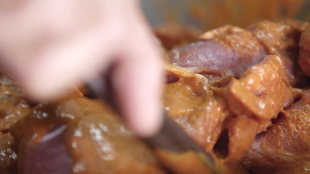 Chef mixes pork in mojo sauce, close up