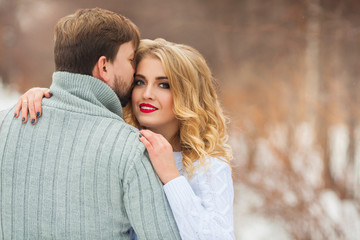 Fototapeta premium beautiful young couple in love in sweaters walking on snowy forest park
