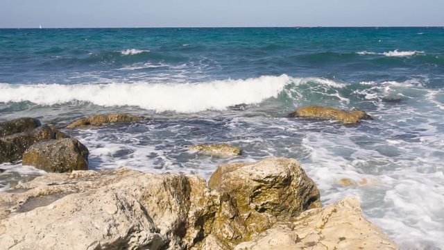 Wide still shot of waves breaking on a rocky