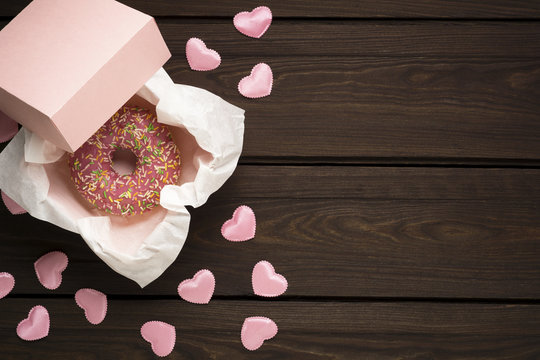 Happy Valentines Day / Creative valentine concept photo of donut with hearts on wooden brown background.