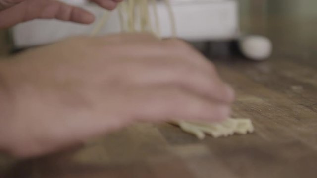 Person holds spaghetti on cutting board, slow motion