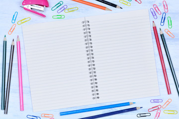 Notepad with colorful pencils, stapler and clips on table