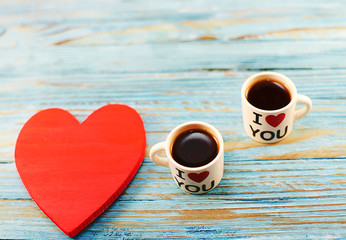 in the pots there is hot coffee and a heart on the wooden background