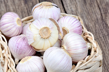 Garlic in a wicker basket on rustic wooden table