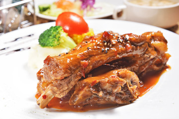 Delicious grilled pork ribs served with a rich sauce garnished with fresh vegetables