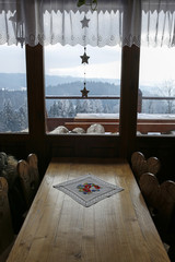 window with winter mountain landscape seen from wooden cottage