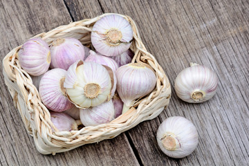 Heap of fresh garlic in a wicker basket on rustic table