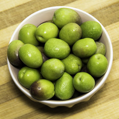 Plate of Green olives ready to eat in chopping board background.