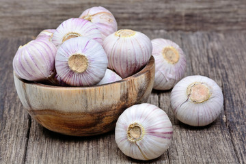 Fresh garlic in a wooden bowl on table