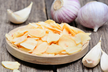 Dried garlic in a wooden plate on rustic table