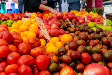 Many red, yellow, brown ripe tomatoes on display at farmers market