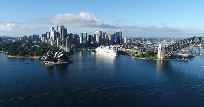 Landmarks of Sydney city CBD on Harbour shores in aerial elevated panoramic view panning towards Sydney Harbour bridge.
