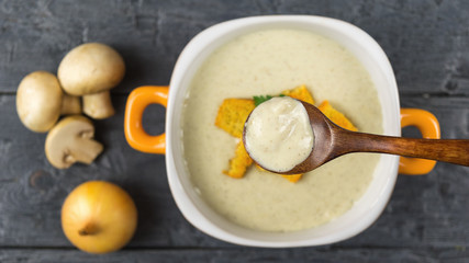 Wooden spoon over a bowl of cream soup from mushrooms. The view from the top.