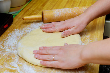 Raw pizza dough with ingredients on wooden table