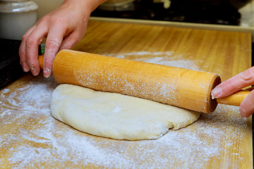 closeup of hands using rolling pin on dough