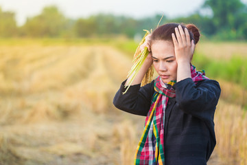 worried woman holding rice in field